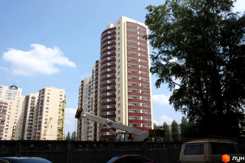 Житловий комплекс Парковий: високі житлові будинки світлих відтінків з численними балконами, на тлі блакитного неба та будівельної техніки.