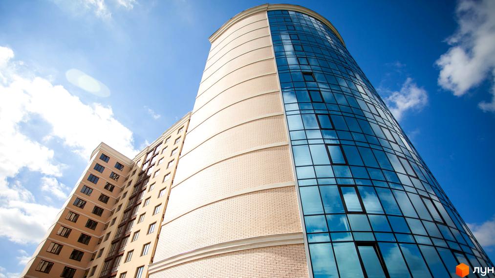 Зображення фасаду Житлового комплексу Paradise з великими вікнами. Вигляд на будівлю з вулиці на фоні блакитного неба.