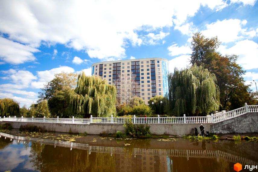 Зображення Житлового комплексу Paradise з видом на річку та зелену зону. Багатоповерховий будинок з великими вікнами на фоні блакитного неба.