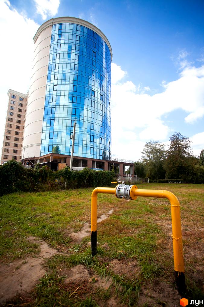 Зображення Житлового комплексу Paradise. Вид на висотний будинок з панорамними вікнами та жовту газову трубу на передньому плані.