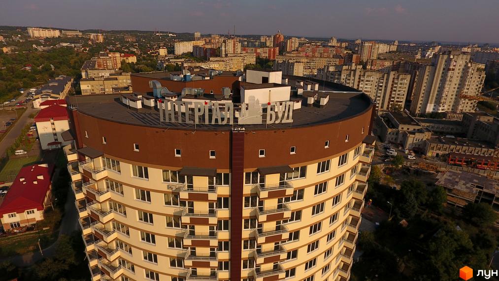 Вигляд зверху на Житловий комплекс по вулиці Бережанська, 54. Багатоповерхова будівля з балконами та коричневим дахом на фоні міської забудови.