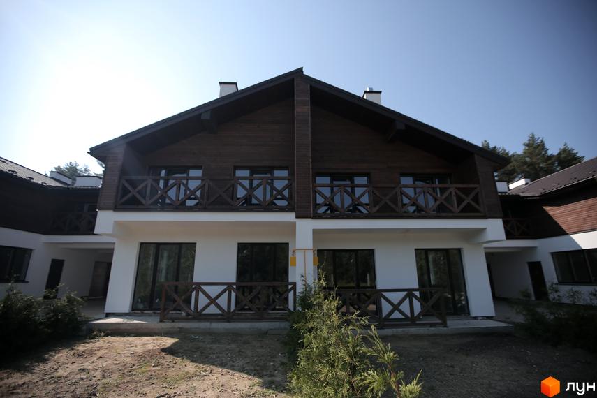 Котеджне містечко КМ Bruhsell. Двоповерхові будинки з дерев'яним оздобленням фасаду та балконами. Навколо будівель облаштована прибудинкова територія.