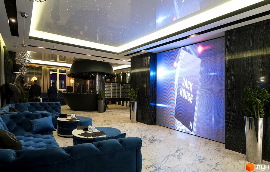 Інтер'єр житлового комплексу Jack House з синіми диванами та великим екраном. Опис новобудови Jack House для просування сайту.