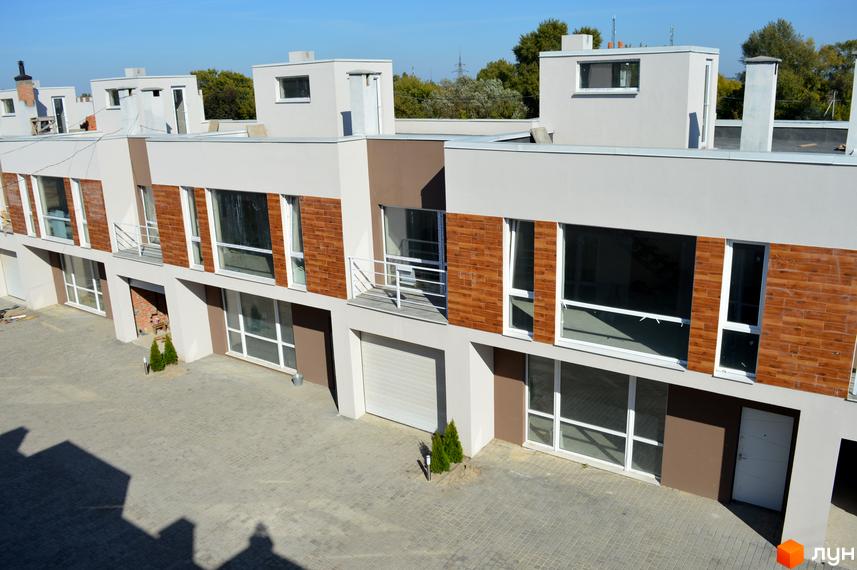 Зображення таунхаусів у Житловому районі „Бельведер Сіті“. Двоповерхові будинки з великими вікнами та оздобленням під цеглу, перед будинками вимощена бруківка.