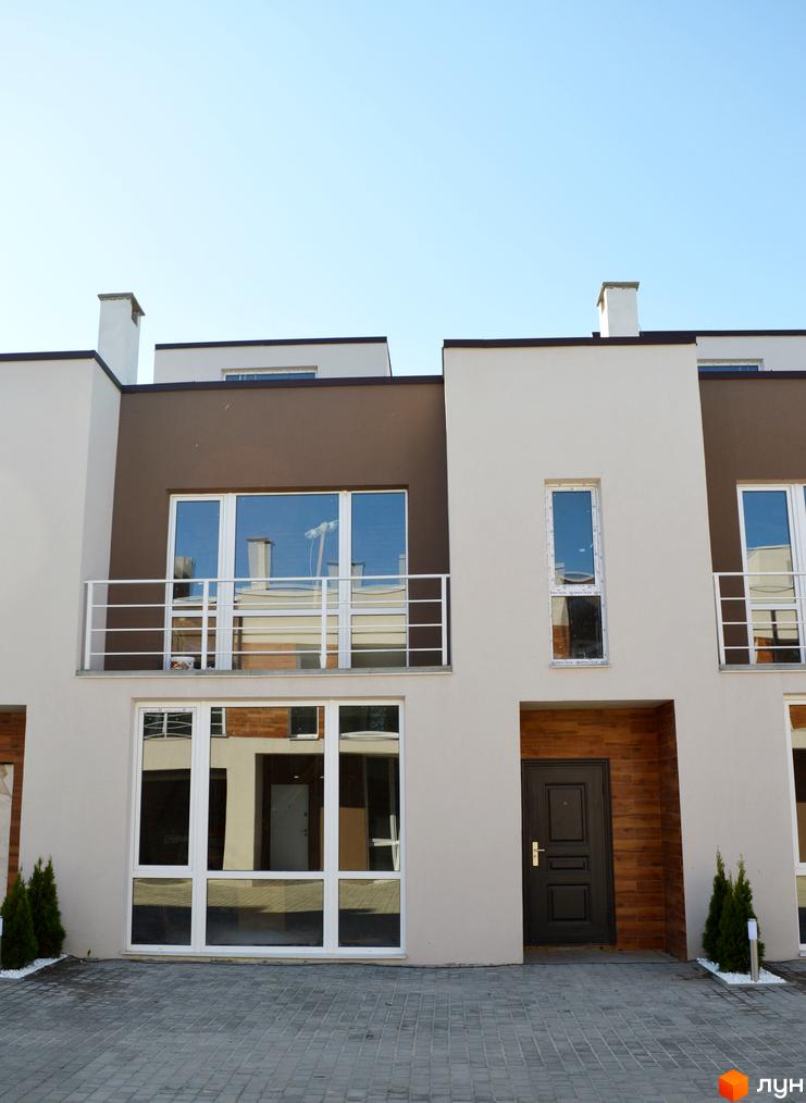 Зображення таунхаусів у Житловому районі „Бельведер Сіті“. Двоповерхові будинки з великими вікнами та коричневими вставками, перед будинками висаджені туї.