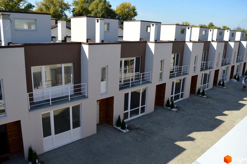 Зовнішній вигляд таунхаусів Бельведер Сіті. Фасад будинку з великими вікнами та балконами, перед будинком висаджені декоративні дерева.