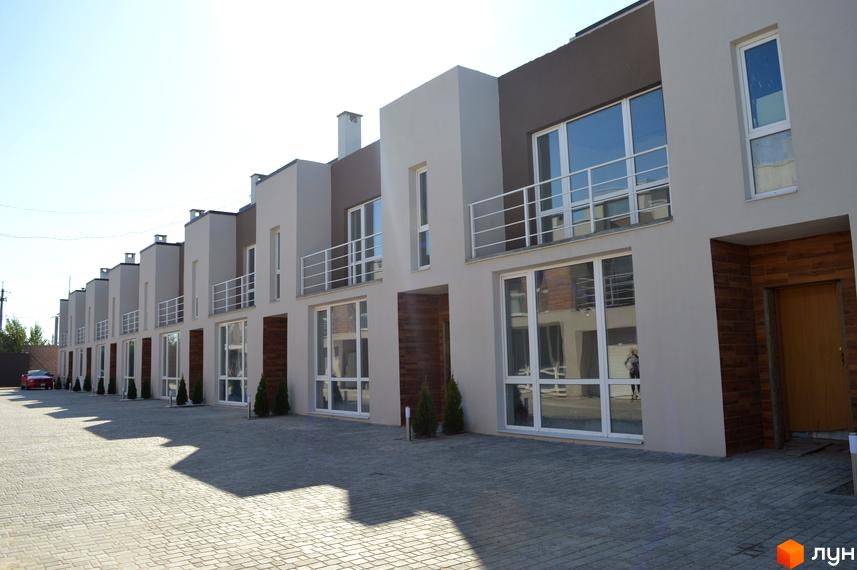 Зовнішній вигляд таунхаусів Бельведер Сіті з великими вікнами та балконами. На передньому плані вимощена бруківкою прибудинкова територія.