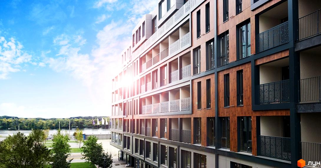 Житловий район Rybalsky з фасадом з дерев'яних та сірих панелей, балконами. Будівля розташована біля річки з зеленою зоною.