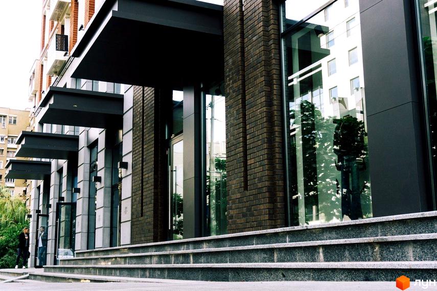 Фасад будинку Житлового комплексу New York Concept House з великими вікнами та цегляними колонами. Вхідна група з гранітними сходами.