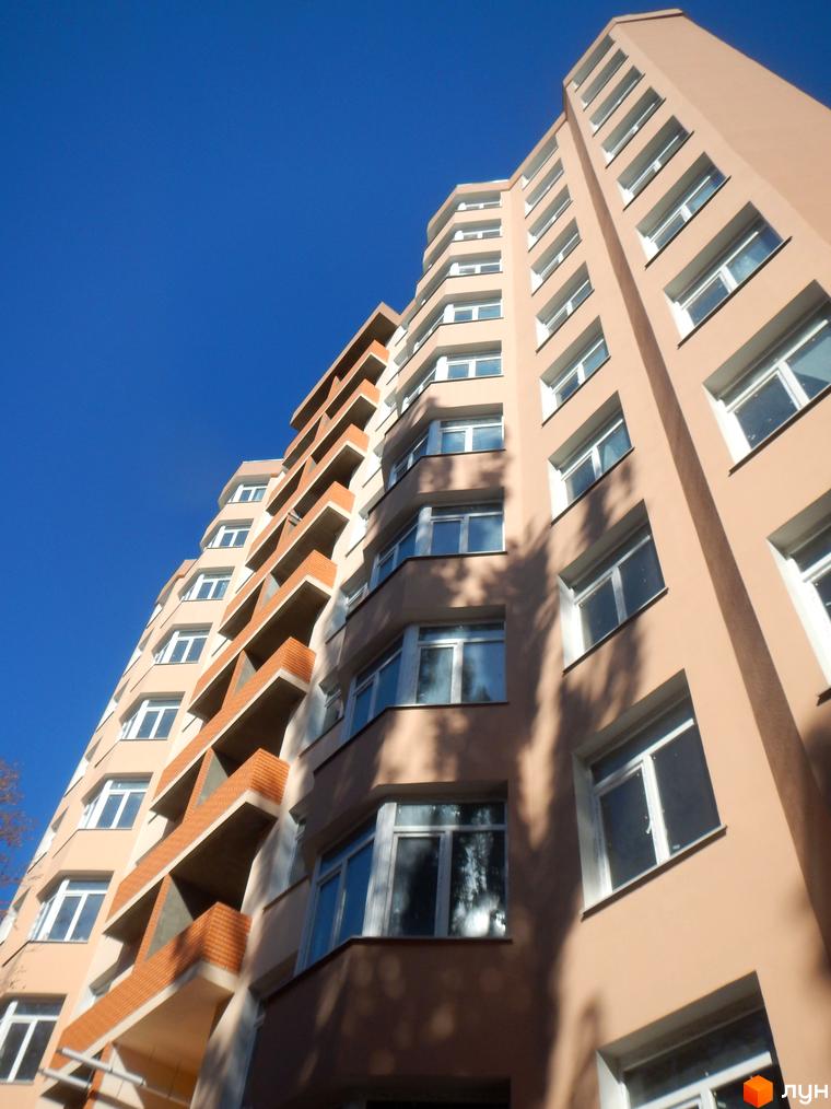 Фасад будинку ЖК Нове місто з балконами та вікнами на тлі блакитного неба. Зовнішній вигляд новобудови.