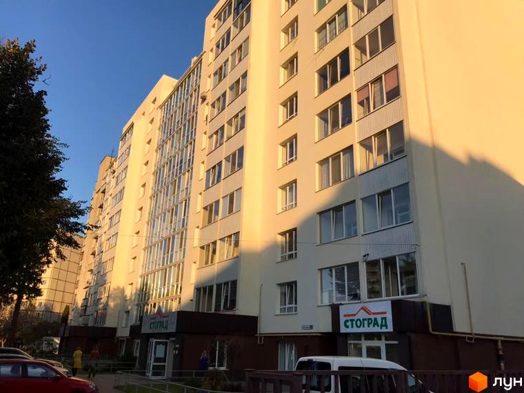 Житловий комплекс СТОГРАД на Клима Савури, 14а. Світлий багатоповерховий будинок з великими вікнами та прибудинковою територією з деревами.