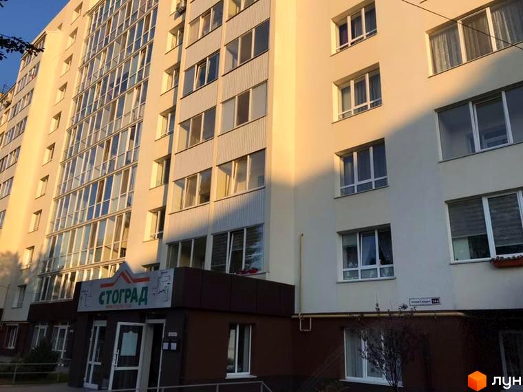 Багатоповерховий житловий будинок світлого кольору з великими вікнами та заскленими балконами. Фасад новобудови СТОГРАД на вул. Клима Савури, 14а.