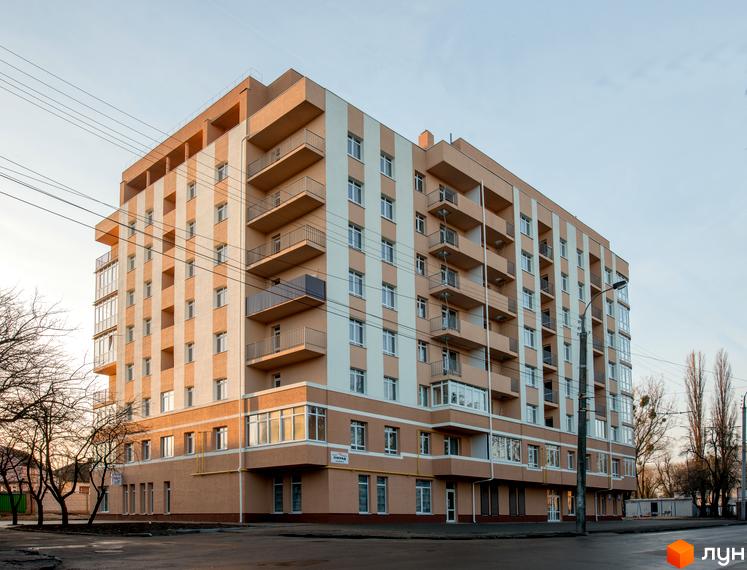 Житловий комплекс на вул. Соборна, 348в з бежево-білим фасадом та балконами. На передньому плані дорога і дерева.