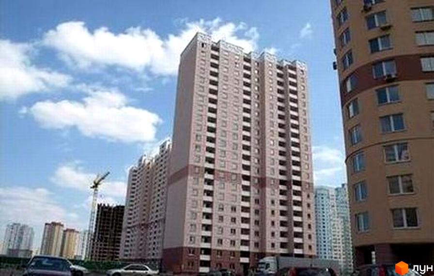 Будинок на Пчілки з фасадом у світлих тонах та прибудинковою територією. Вид на сусідні будівлі та облаштовану зону для автомобілів.