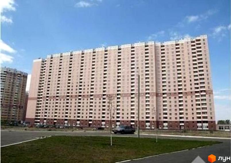 Будинок на Пчілки з великими вікнами та фасадом у світлих тонах. Прибудинкова територія з зеленими насадженнями та парковими місцями.