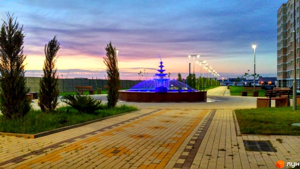 Житловий комплекс Цветной бульвар (Чорноморськ) з фонтаном та освітленням у вечірній час. Благоустрій території з доріжками та лавками.
