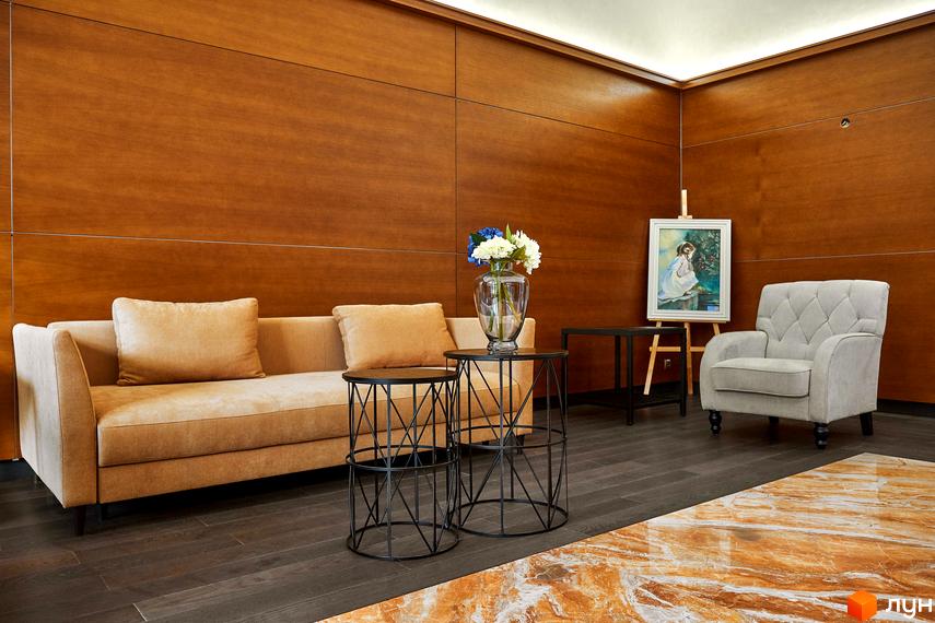 Інтер'єр житлового комплексу Park Avenue VIP з м'якими меблями, столиками та живими квітами на фоні дерев'яної стіни.
