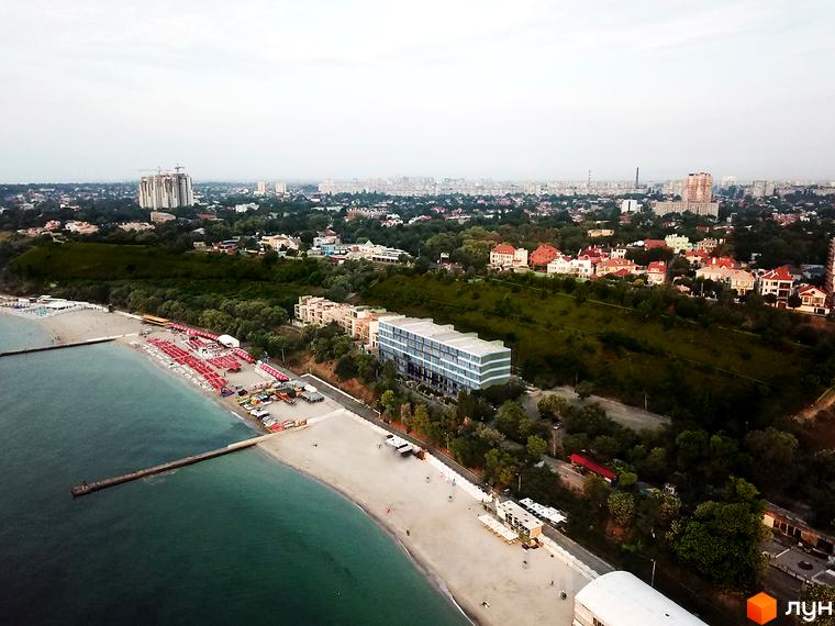 Житловий комплекс MAGNÍT. Будинок на Фонтані з фасадами, що чергуються, розташований біля моря та пляжу з парасольками.