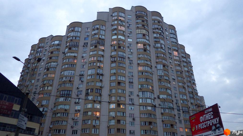 Житловий комплекс на вул. Дніпровська набережна, 19 з сучасним фасадом та великими вікнами, прибудинкова територія з освітленням.