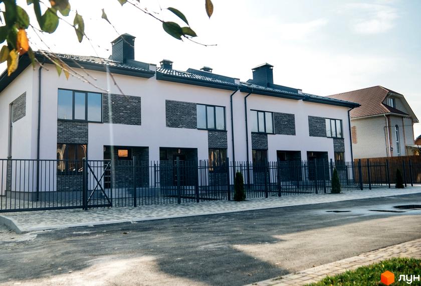 Таунхауси „На Підлісній“. Зовнішній вигляд двоповерхових будинків з цегляними вставками, вікнами та парканом. Прибудинкова територія з бруківкою та зеленими насадженнями.