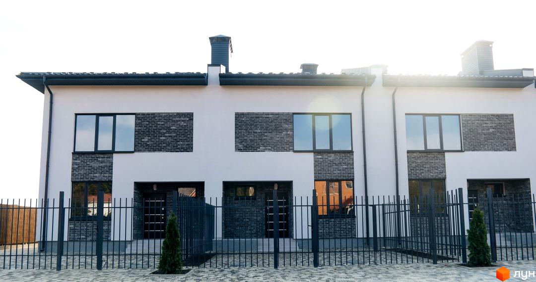 Таунхауси „На Підлісній“: фасади будівель з цегляними вставками та великими вікнами, огороджена прибудинкова територія з парканом та зеленими насадженнями.