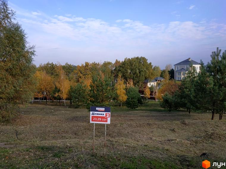 Вид на Котеджне містечко Lisnyky Club. На передньому плані ділянка землі, на задньому - котеджі та дерева.