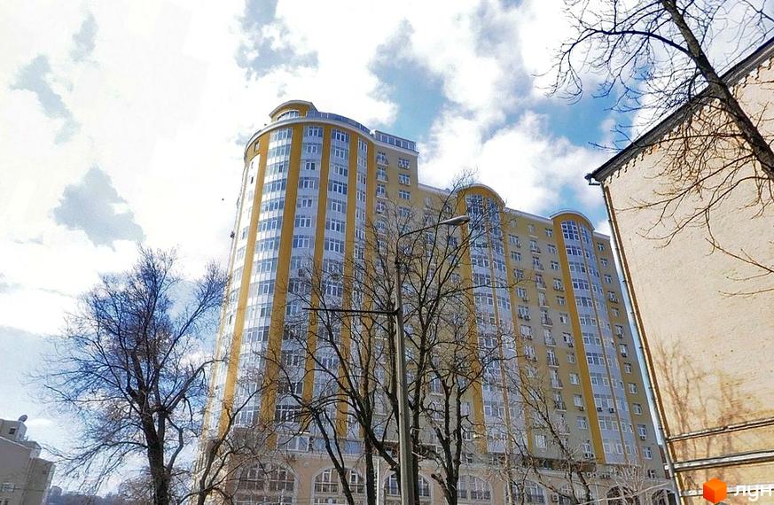 Житловий комплекс на вул. Антоновича, 72, з сучасним фасадом та прибудинковою територією з деревами.