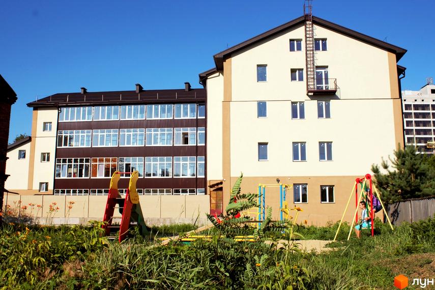 Житловий комплекс Belobrovski: багатоповерхові будинки з коричневою та світлою обробкою, дитячий майданчик з гіркою та гойдалками на прибудинковій території.