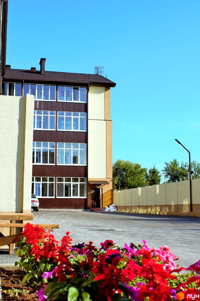 Житловий комплекс Belobrovski: фасади будівель з великими вікнами та прибудинкова територія з квітами та парковкою.