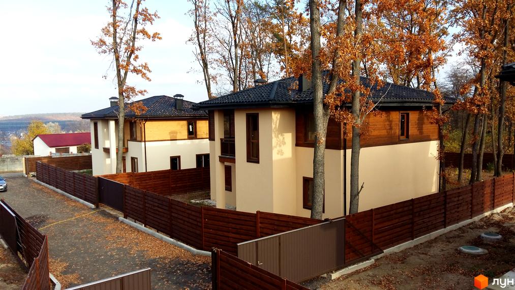 Котеджне містечко Віта Паркова: двоповерхові будинки з дерев'яними елементами та темними дахами, огороджені дерев'яними парканами.