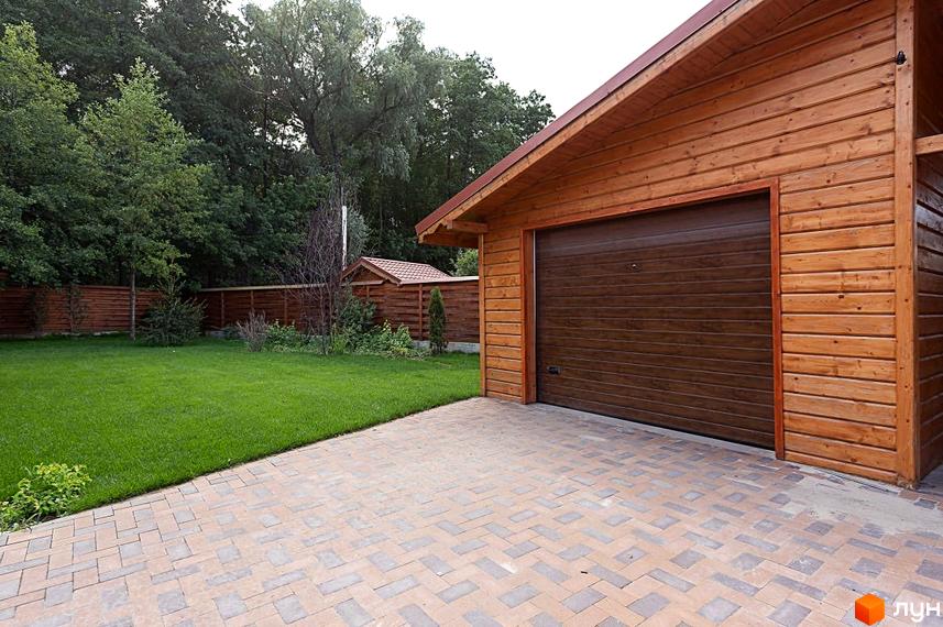 Котеджне містечко Summerville: дерев'яний будинок з гаражними воротами та вимощеною територією. Зелений газон та паркан з дерева.