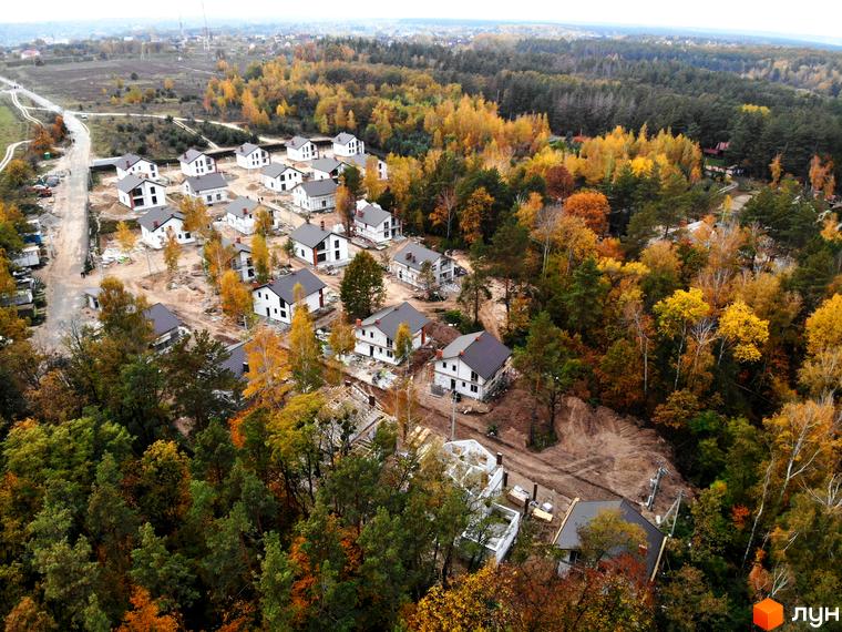 Котеджне містечко Ліс та Озеро: білі будинки з темними дахами на тлі осіннього лісу. Забудова з новобудовами та зеленими насадженнями.
