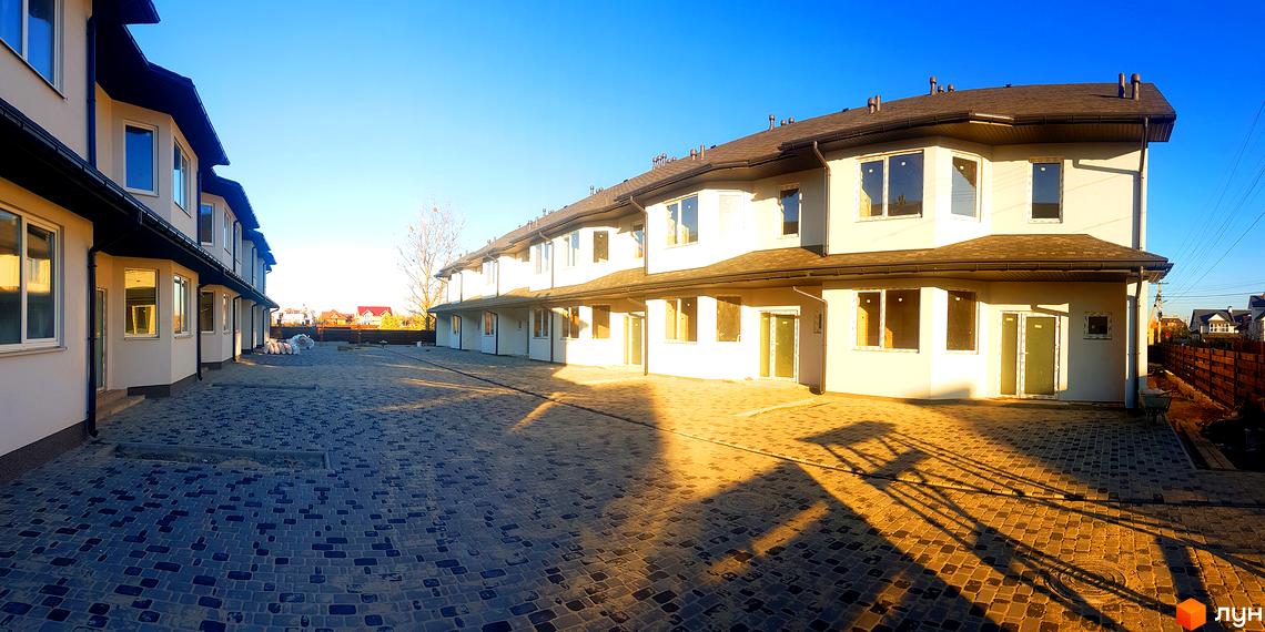 Зовнішній вигляд таунхаусів New Town з великими вікнами та світлим фасадом. Бруківка на прибудинковій території створює затишну атмосферу.