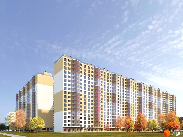 Житловий комплекс Привітний квартал: багатосекційний будинок світлих тонів з численними вікнами, на тлі блакитного неба та осінніх дерев.