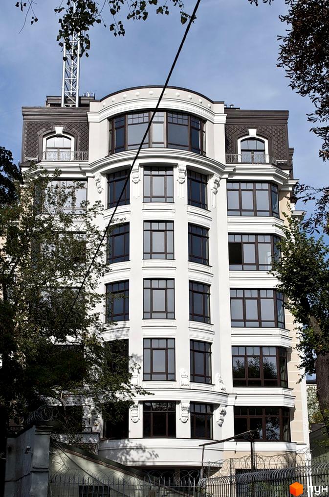 Житловий комплекс на вул. Десятинна, 11, з сучасною архітектурою та великими вікнами, оточений зеленими насадженнями.