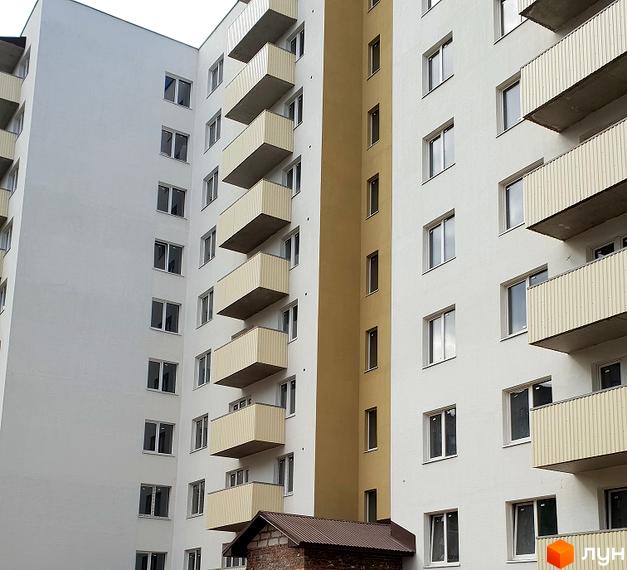 Фасад новобудови на вул. Тарнавського, 7, з балконами та вікнами. Зовнішній вигляд будівлі з білими та жовтими елементами.