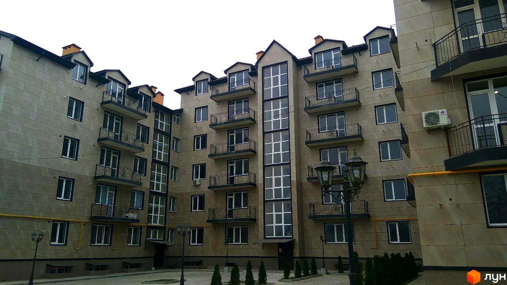 Зовнішній вигляд новобудови ЖК London з балконами та великими вікнами. Прибудинкова територія з ліхтарями та зеленими насадженнями.