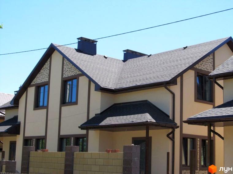 Зображення дуплексу в Котеджному містечку „Баварія“. Двоповерховий будинок з сірим дахом та світлим фасадом, перед будинком цегляний паркан.