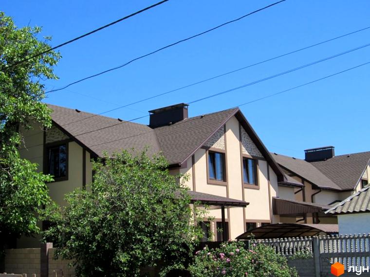 Зображення дуплексу в Котеджному містечку „Баварія“ з коричневим дахом та світлим фасадом. Навколо зелені насадження та доглянута територія.