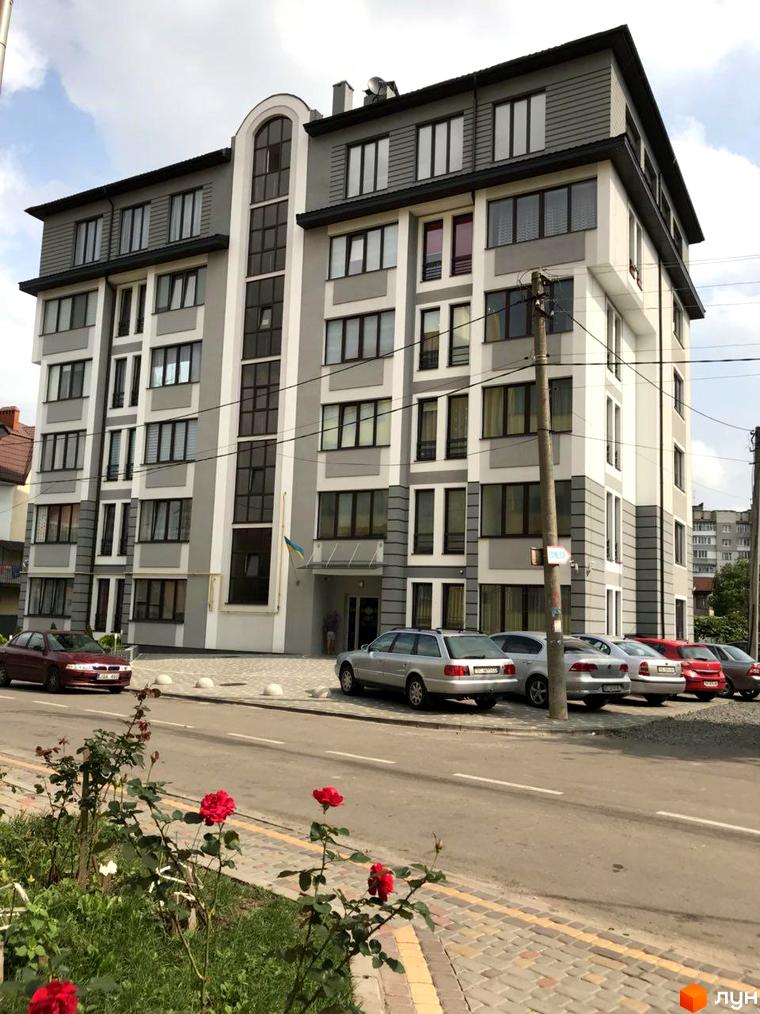 Зображення фасаду Житлового комплексу Срібний Дім Преміум. Багатоповерхова будівля з великими вікнами та припаркованими автомобілями.