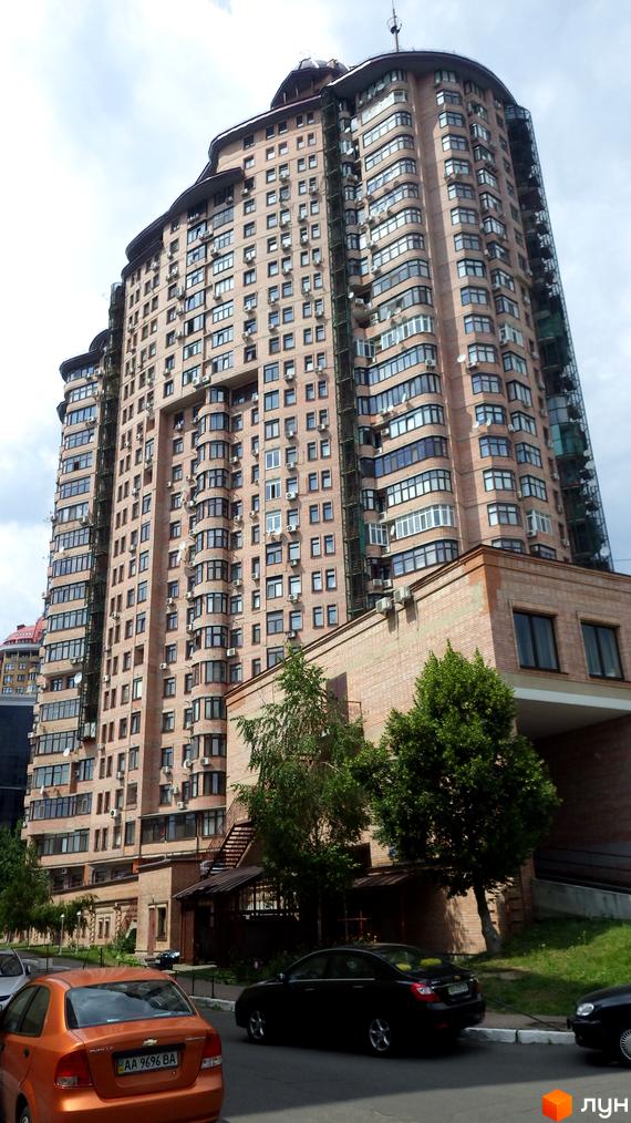 Житловий комплекс на вул. Євгена Коновальця, 36в, з сучасним фасадом та прибудинковою територією, озелененою деревами.