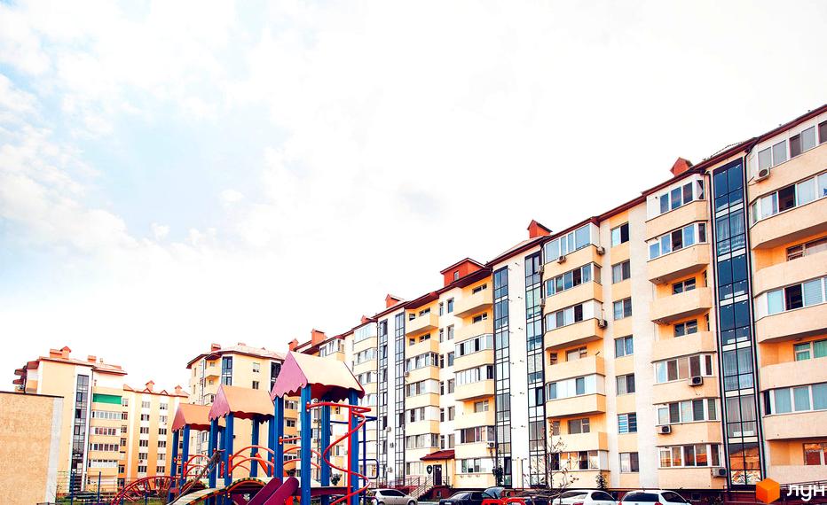 ЖК Маріїнський. Багатоповерховий будинок з великими вікнами та балконами. На передньому плані дитячий майданчик.