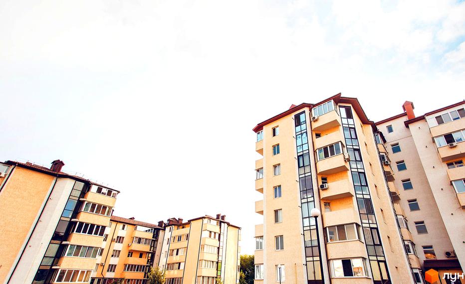 Житловий комплекс Маріїнський. Високі будинки з бежевими фасадами та великими вікнами на тлі неба. Архітектура з балконами та кондиціонерами.