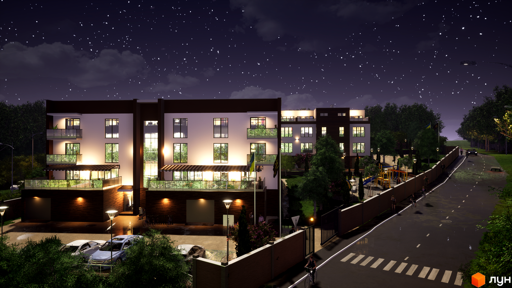 Таунхауси Sunny Village вночі. Фасад будівлі з вікнами та балконами, освітлений ліхтарями. Поруч розташований дитячий майданчик та парковка з автомобілями.