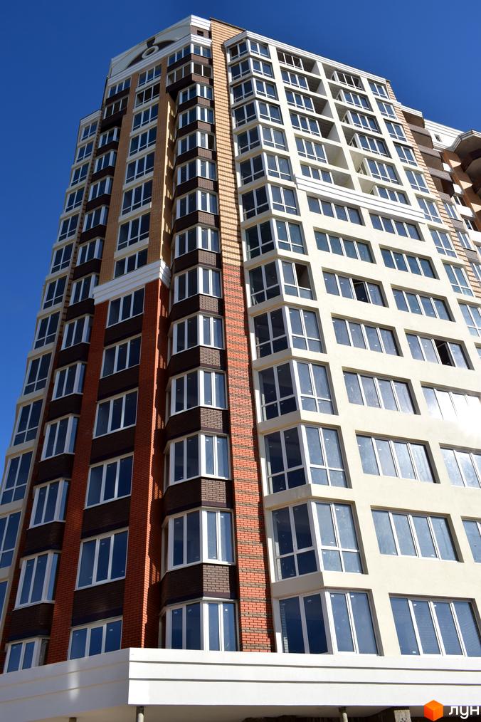 Зображення фасаду багатоповерхового будинку в Житловому комплексі Левада. Вигляд новобудови з великою кількістю вікон та оздобленням з цегли.