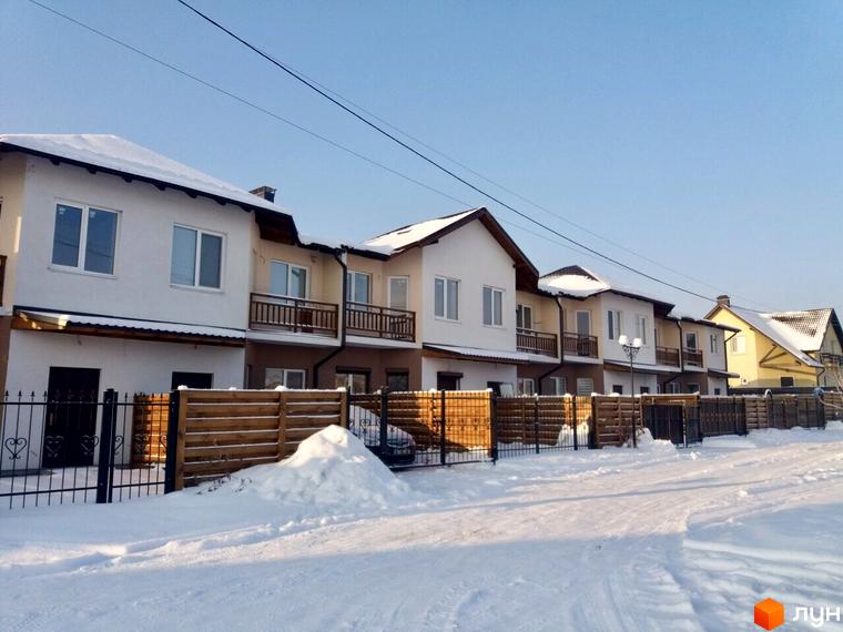 Зимовий вигляд котеджів КМ Riviera. Двоповерхові будинки з балконами та снігом на дахах. Перед будинками дерев'яний паркан та засніжена прибудинкова територія.