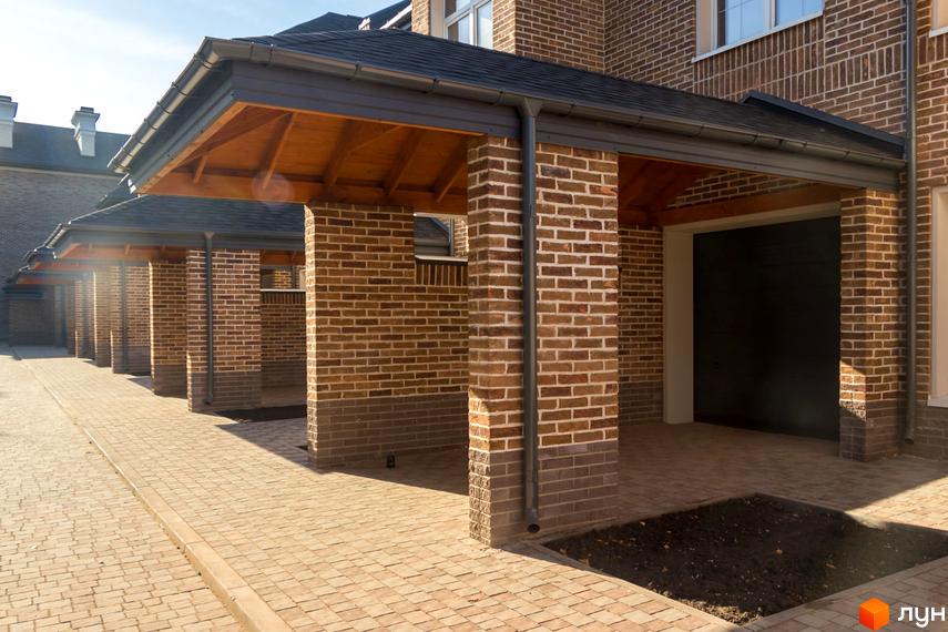 Таунхаус Барвіста з цегляним фасадом та навісом. Прибудинкова територія вимощена бруківкою.