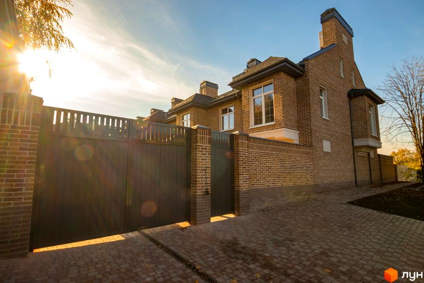 Таунхаус Барвіста – цегляний будинок з великими вікнами та темними воротами. Територія перед будинком вимощена бруківкою під яскравим сонячним промінням.