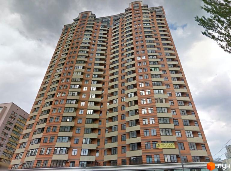 Високий житловий комплекс на бульварі Лесі Українки, 7а, персикового кольору з численними вікнами та балконами. Видно хмарне небо.