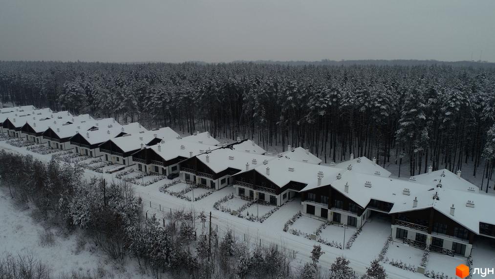 Котеджне містечко КМ Bruhsell у зимовому ландшафті. Сучасні будинки з білими дахами, вкритими снігом, розташовані серед засніженого лісу.